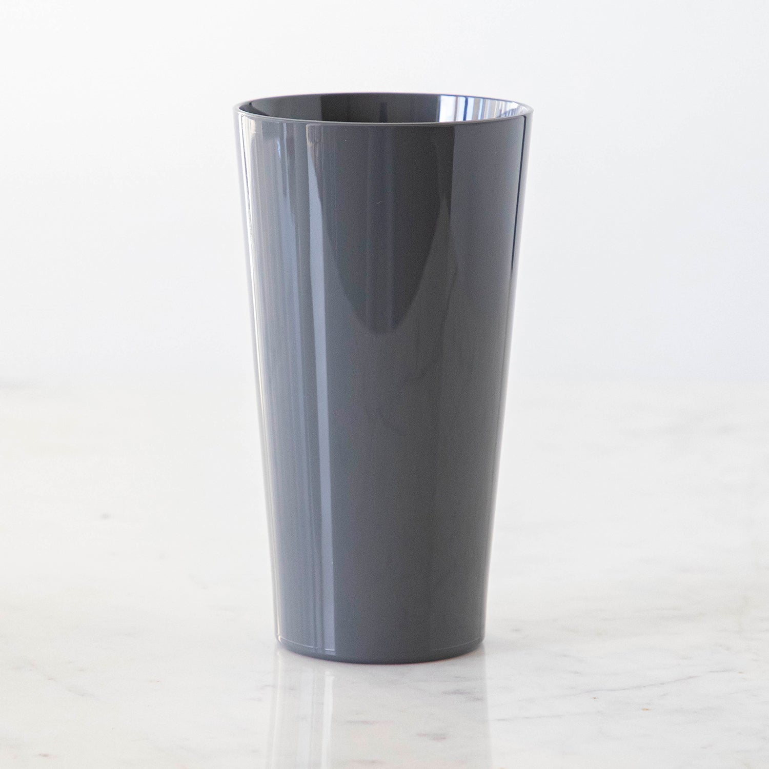 A Gray Pint symGlass on a marble table.