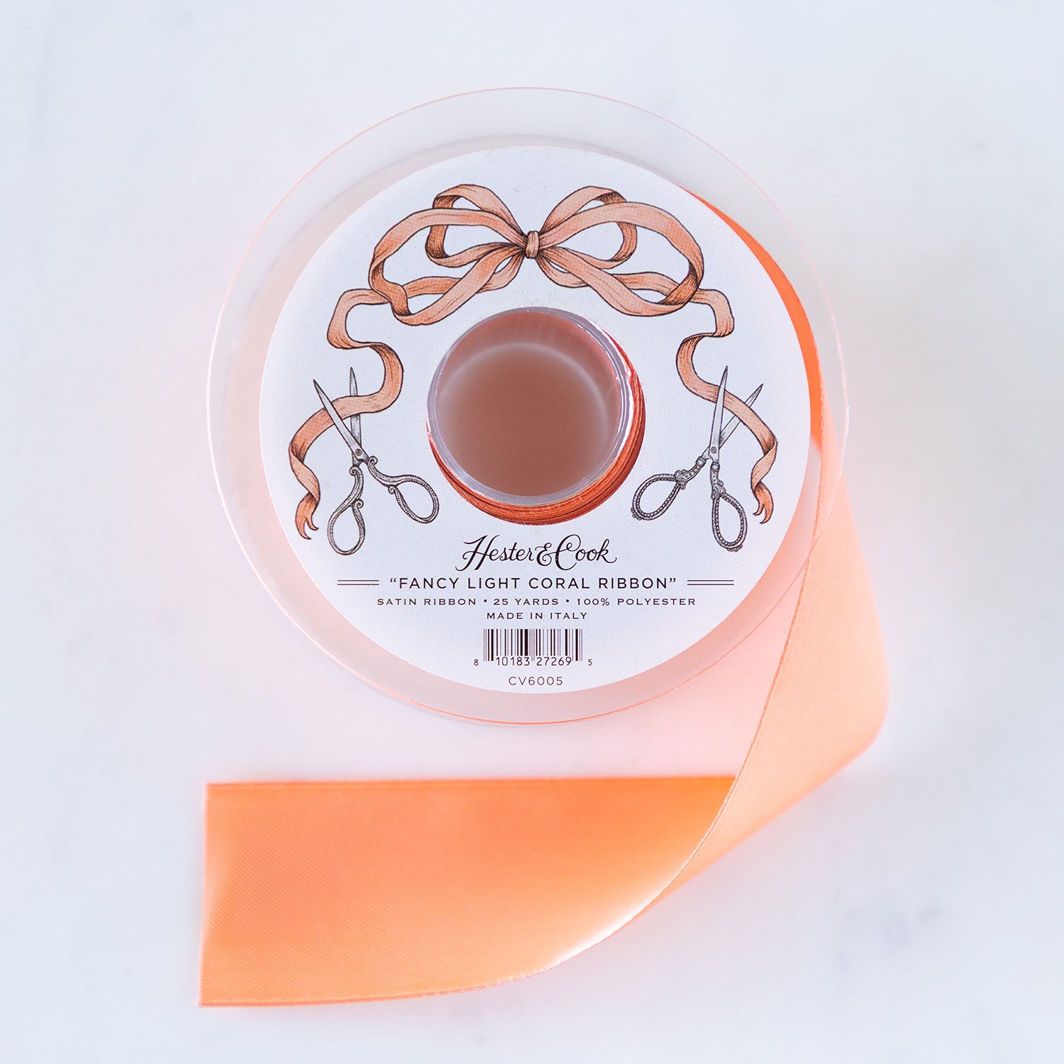 A spool of light-coral satin ribbon with a label featuring illustrated scissors and coral bow, branded &quot;Hester &amp; Cook Fancy Light Coral Ribbon.