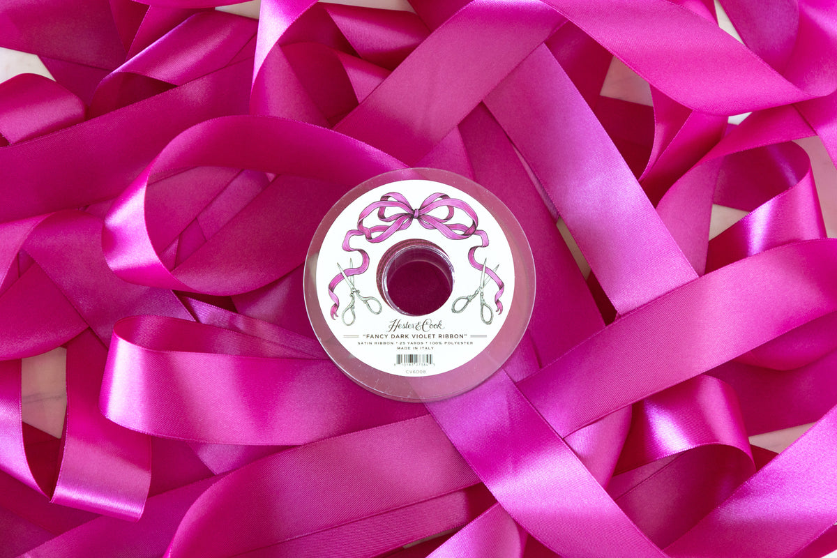 Spool of dark violet ribbon with a decorative label on a background of dark violet ribbons.