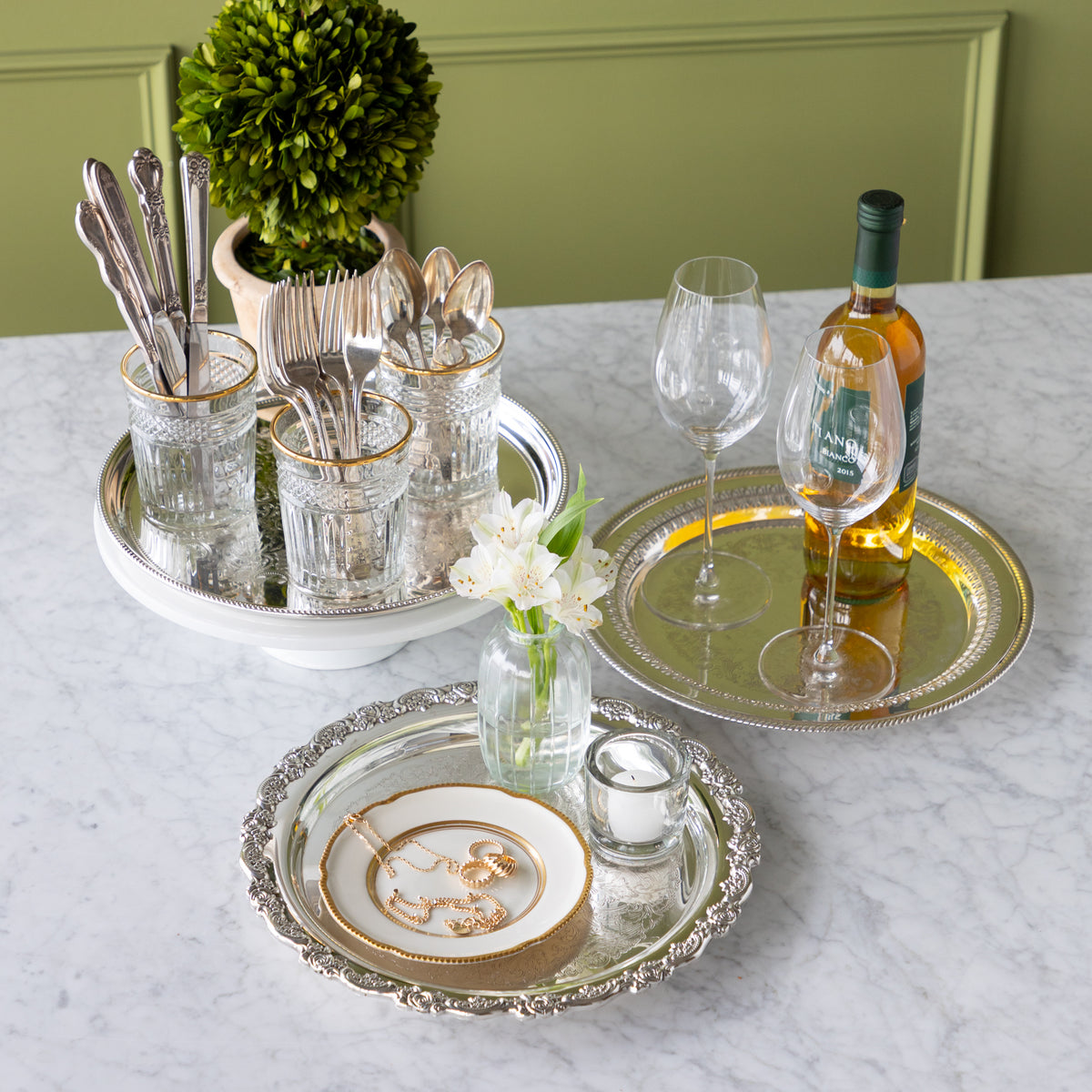 Dining table setting with silverware, glasses, and a bottle of wine on a marble surface.
