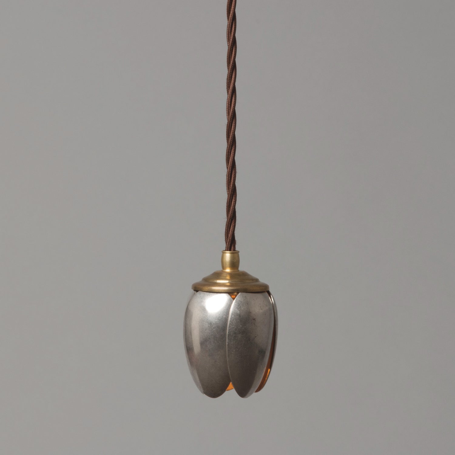 A single tulip-shaped pendant light made from vintage serving spoons, with a brass finish.
