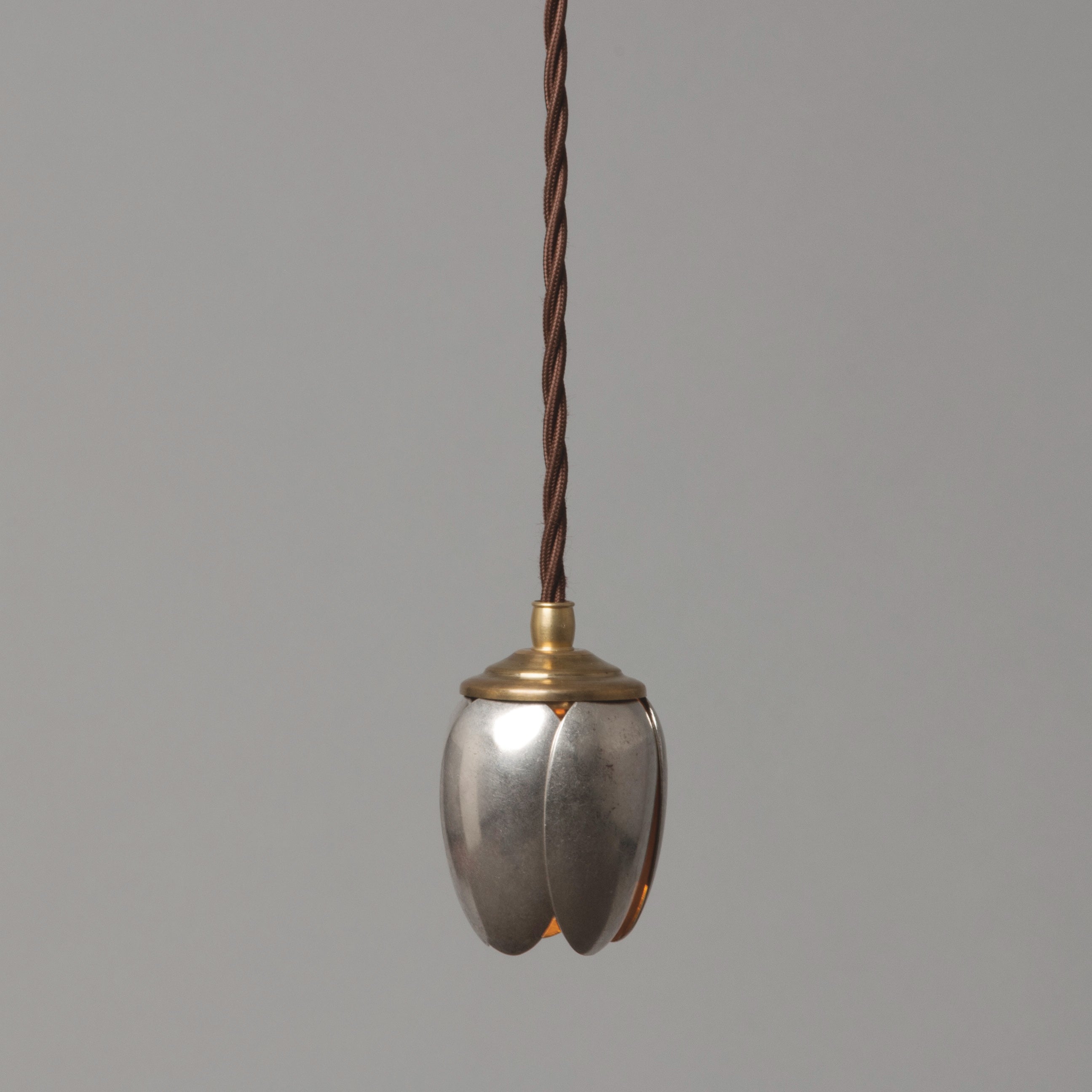 A single tulip-shaped pendant light made from vintage serving spoons, with a brass finish.