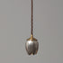 A single tulip-shaped pendant light made from vintage serving spoons, with a brass finish.