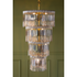 A tiered chandelier with vintage silver-plate knives and a gold-toned metal frame, hanging against an olive green paneled wall.