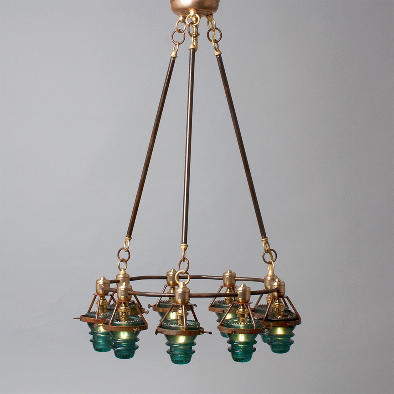 Antique bronze chandelier with multiple glass lampshades and antique insulators suspended from the ceiling, made in the USA by Hester &amp; Cook&