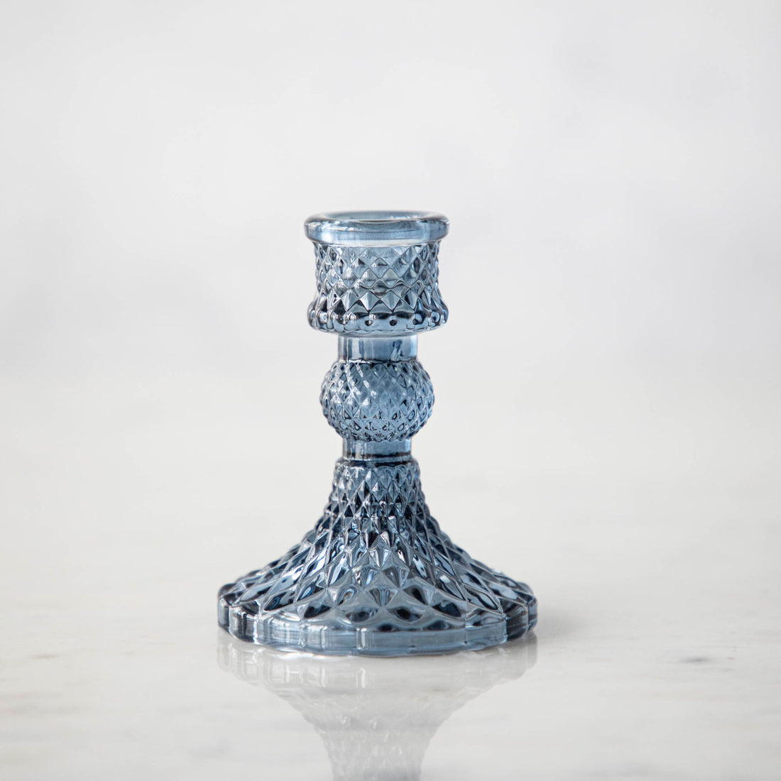 A group of Accent Decor Vintage Blue Candlestick candle holders on a marble table.