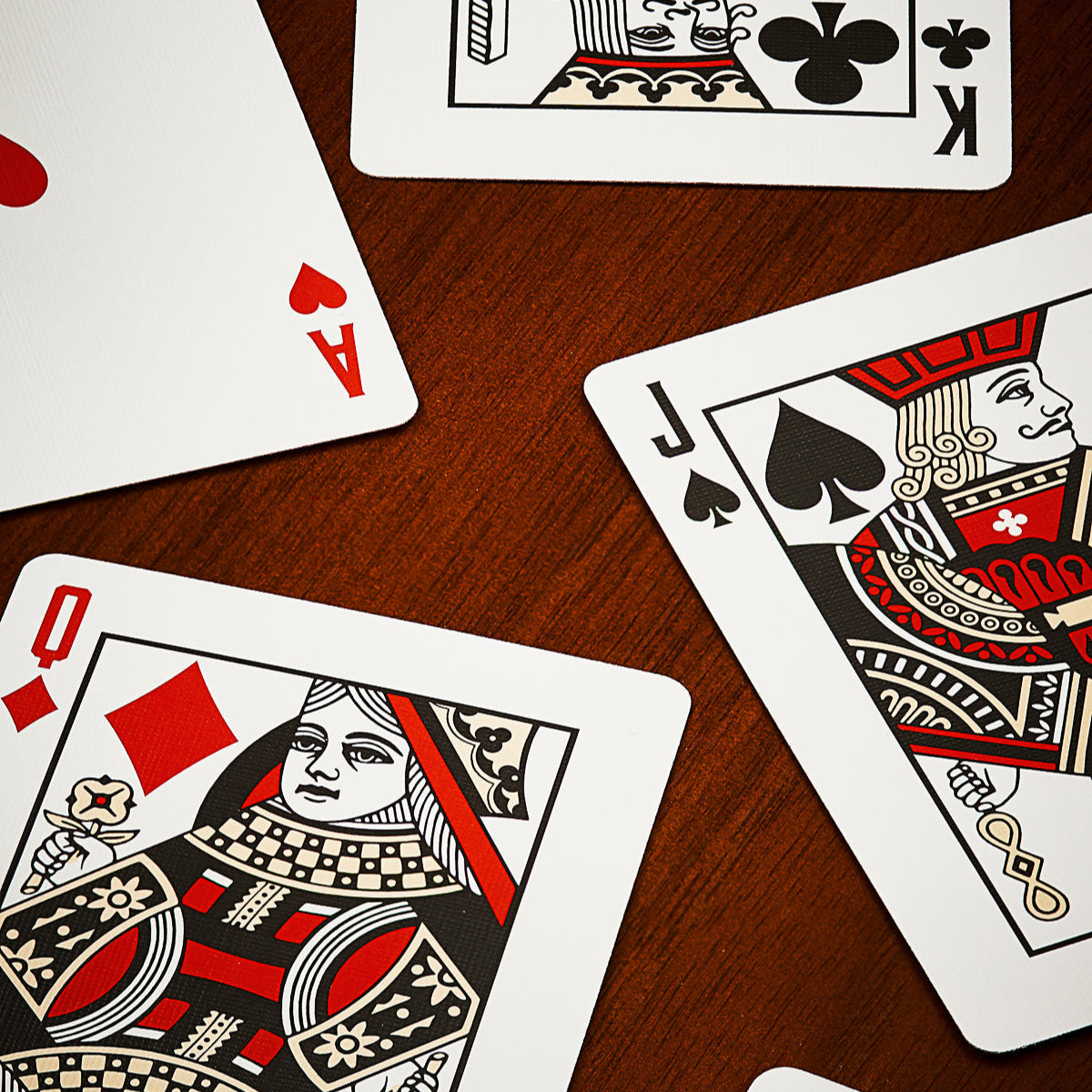 Four playing cards on a wooden surface.