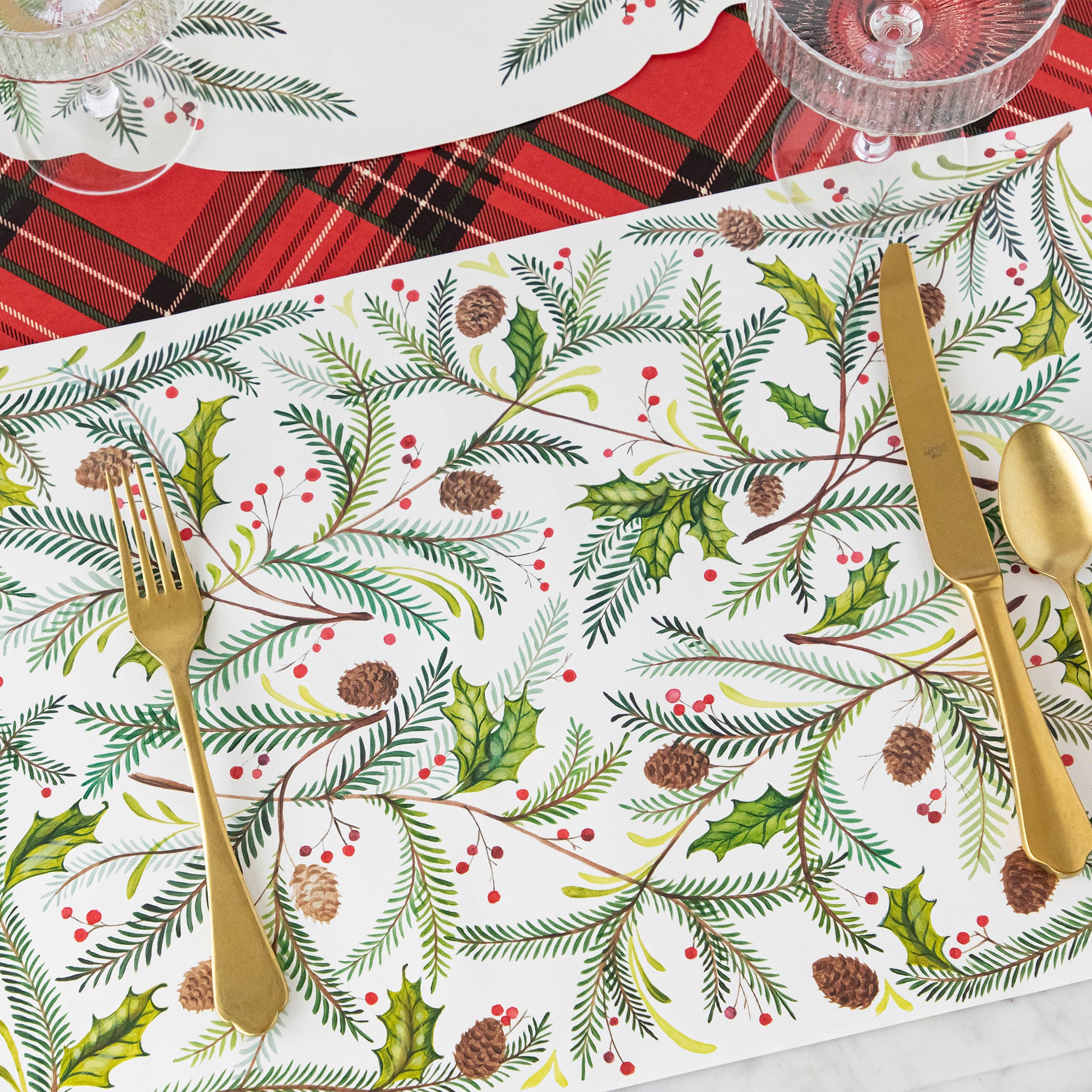 A place setting with the Christmas Sprigs Placemat and gold flatware on the Red Plaid Runner.
