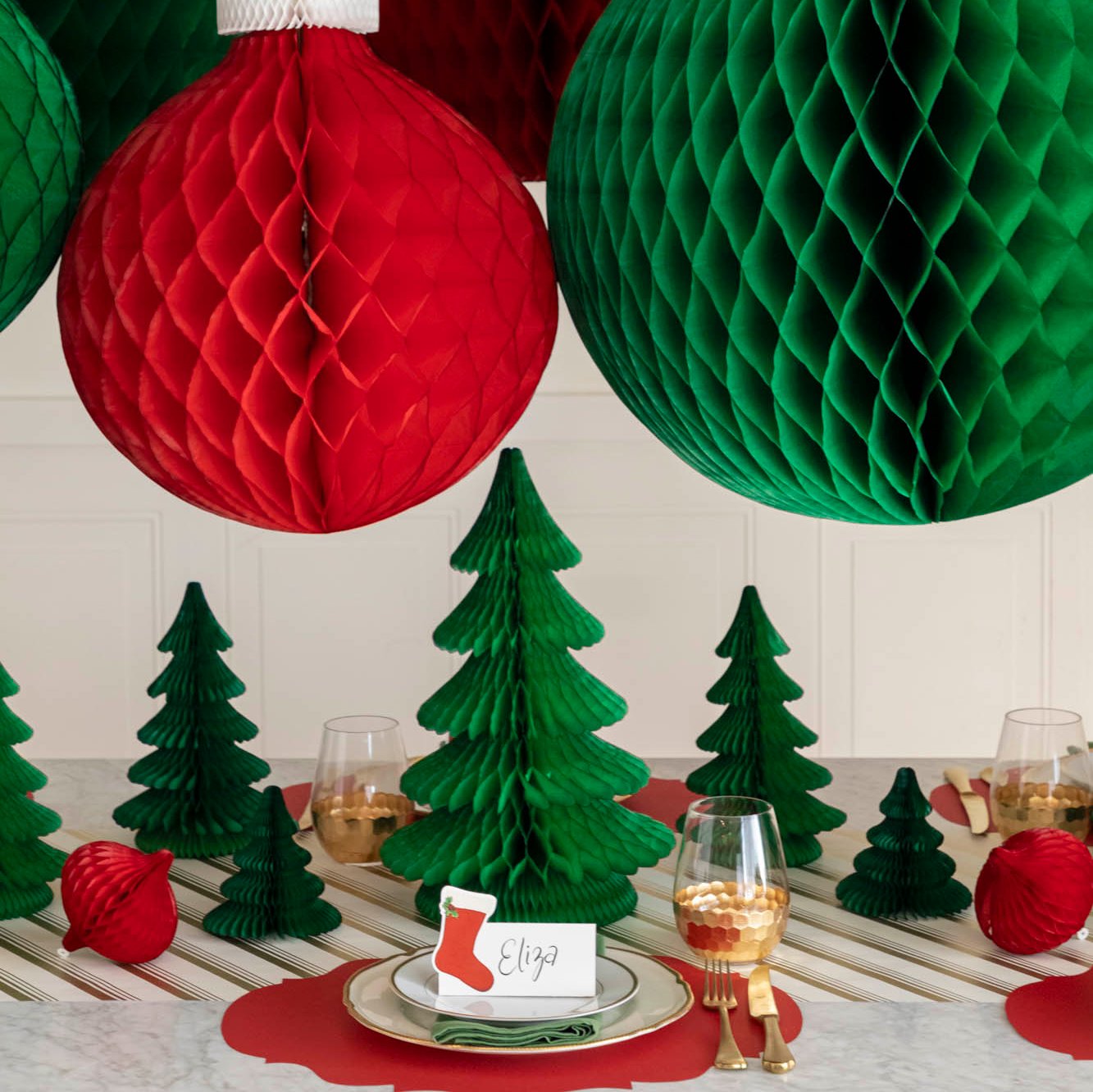 A festive Christmas table setting with honeycomb trees scattered across the table and Honeycomb Large Classic Ornaments hanging above.