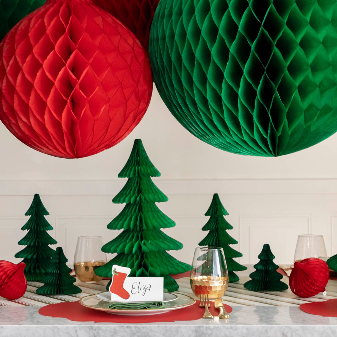 A festive, Christmas table setting with Honeycomb Large Classic Ornaments hanging above.