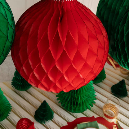 A topdown view of the red, Honeycomb Classic Ornament, hanging above a festive Christmas table setting.