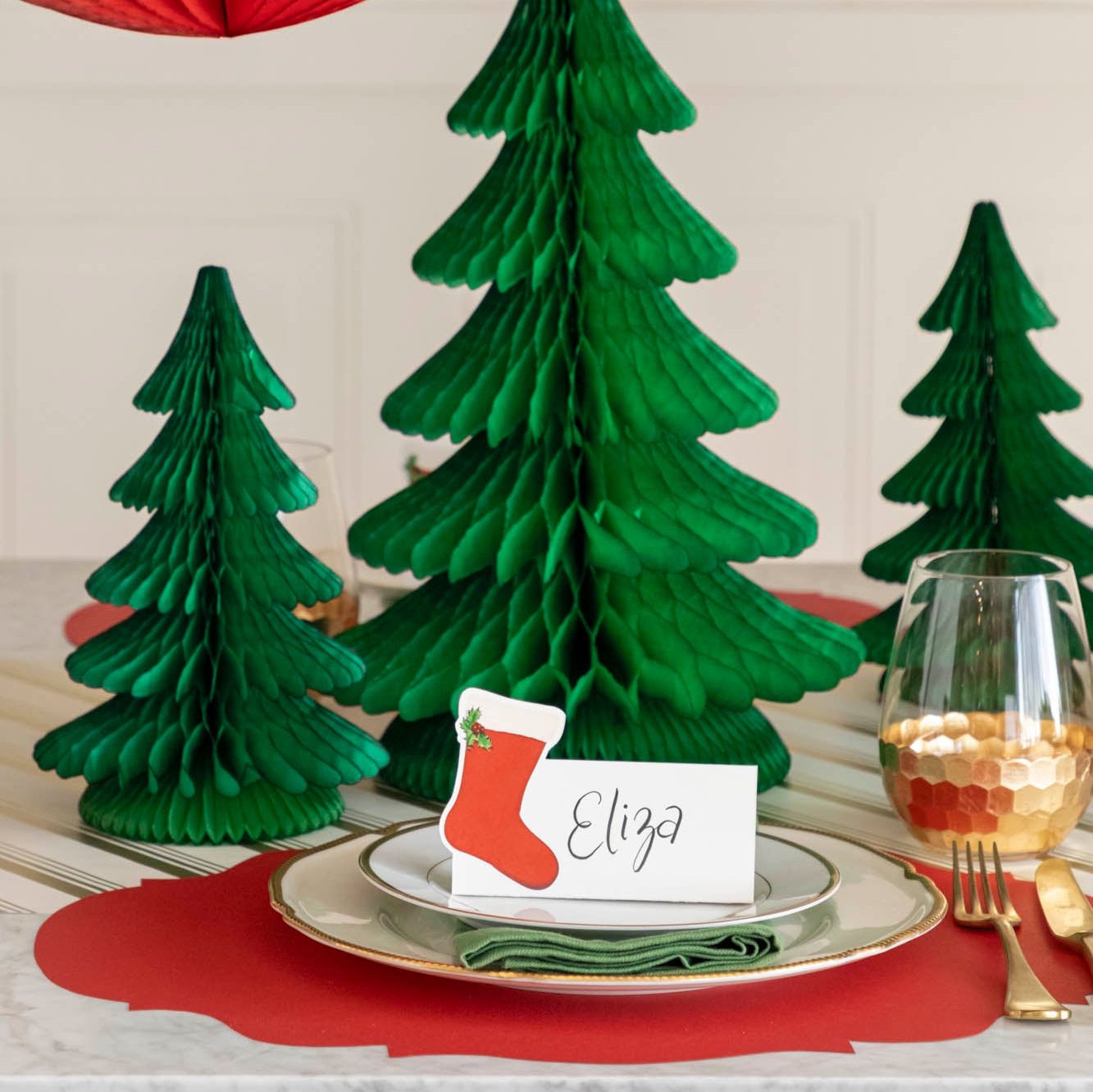 A festive Christmas table setting with Honeycomb Large and Medium Trees in the center of the table, behind a place setting.