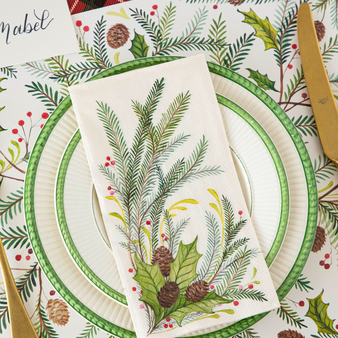 Christmas-themed place setting with the Christmas Sprigs Guest Napkin atop dinner plates and the Christmas Sprigs Placemat.