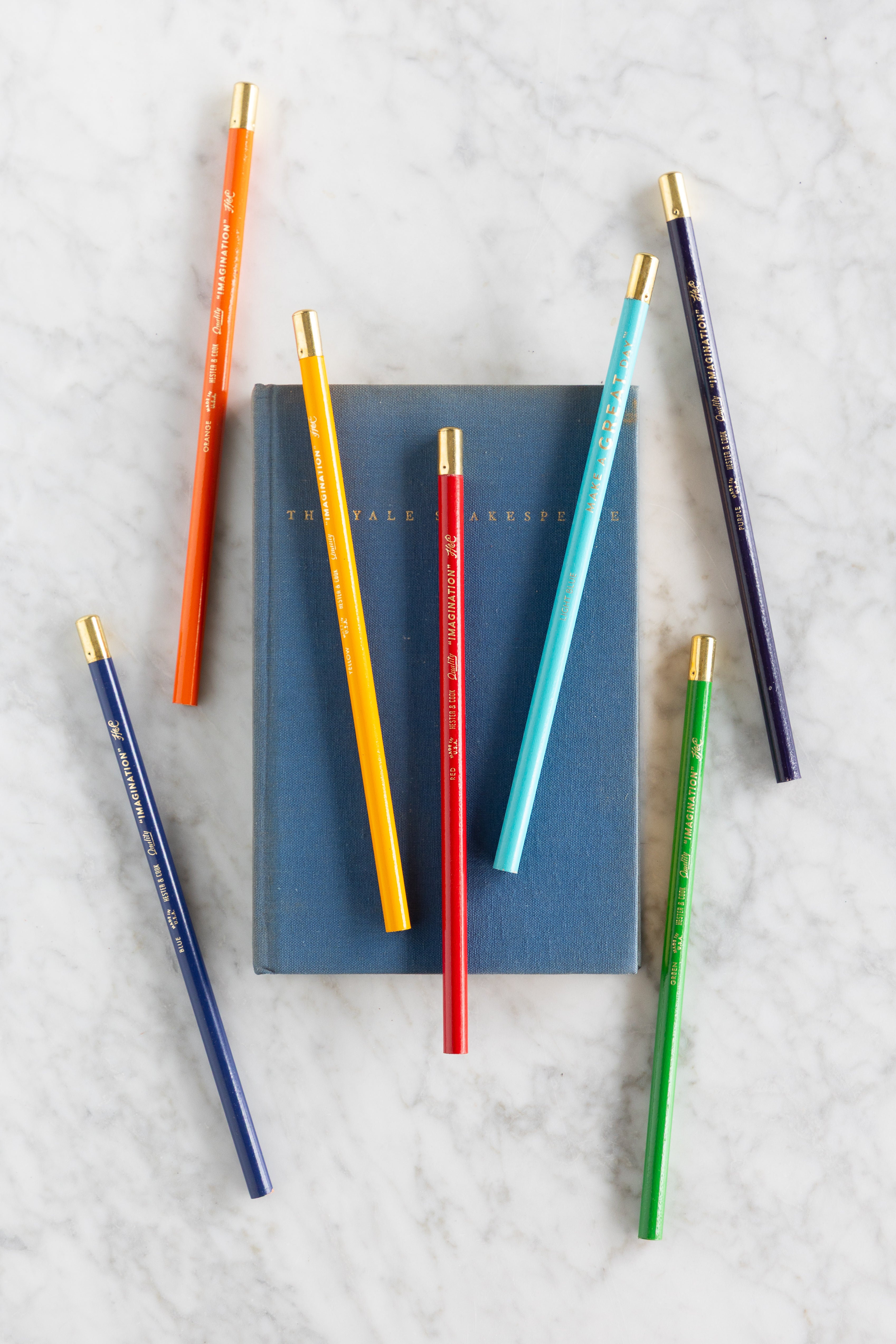 Set of colorful pencils and notebooks on a textured surface.