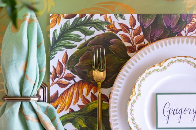 Table setting with a decorative placemat, plate, and fork on a green background.