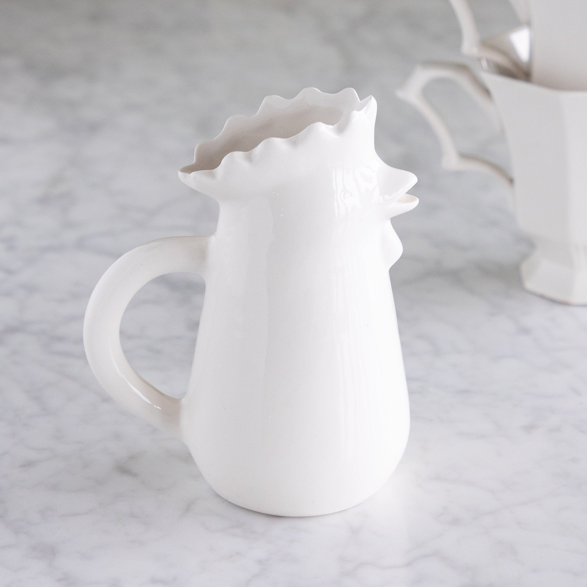 Stoneware Chicken Creamer on a marble table.