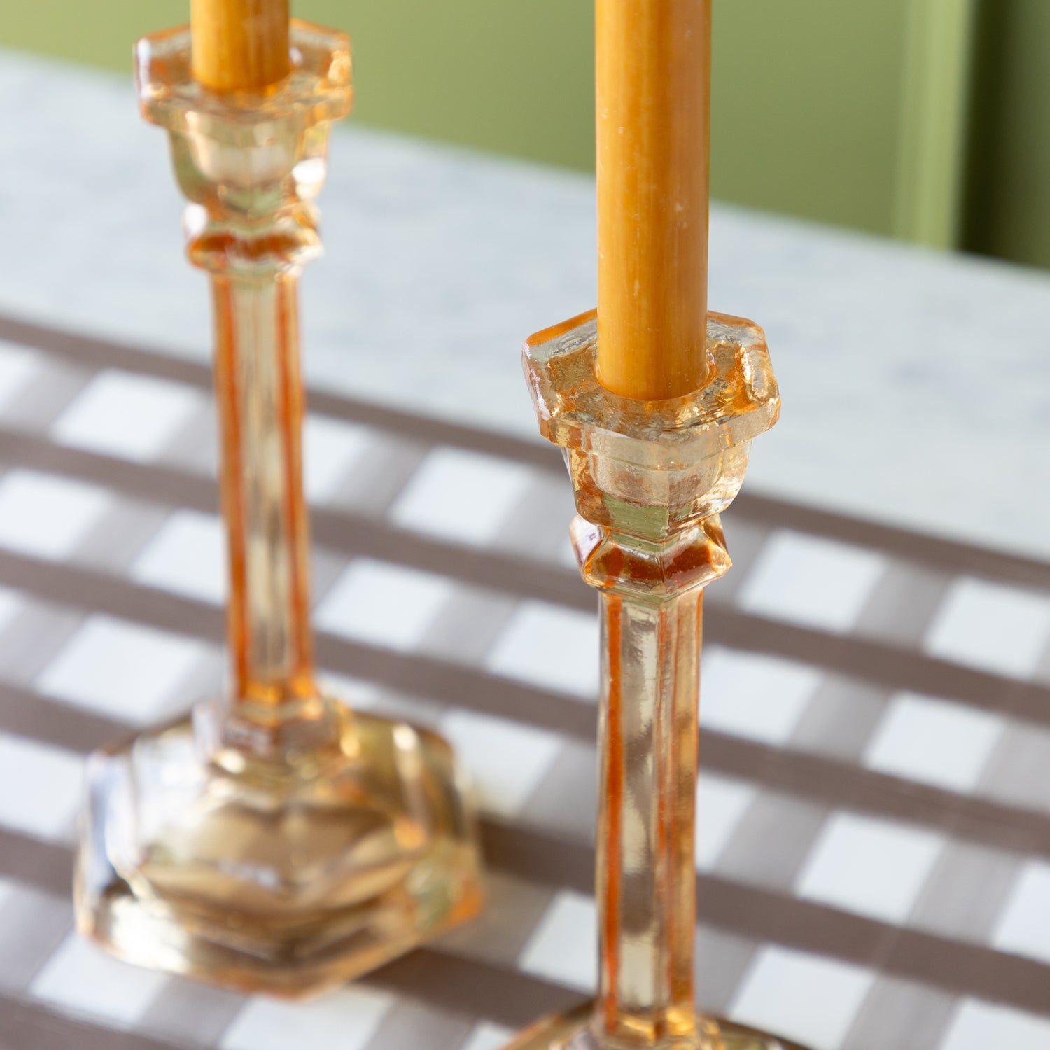 Two amber-colored candles in Amber Glass Candle Holders.