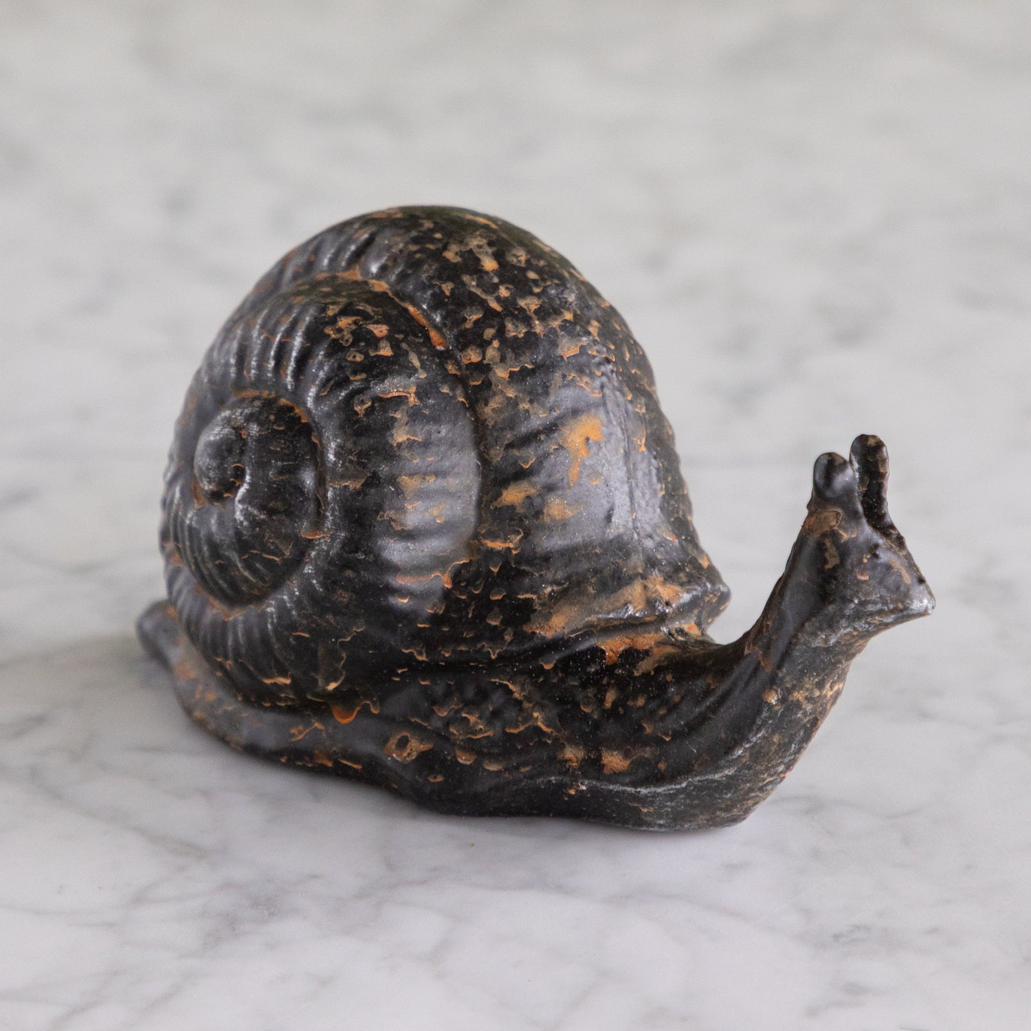 Decorative snail sculpture on a marble surface.