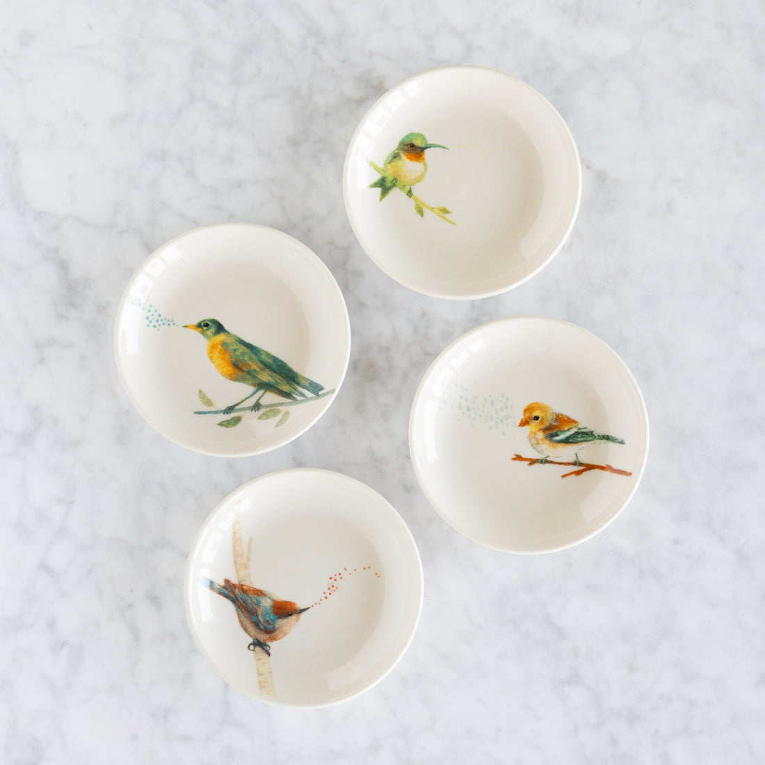 Set of five small ceramic bowls with bird illustrations on a light gray background