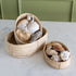 Three woven baskets with seashells on a marble surface