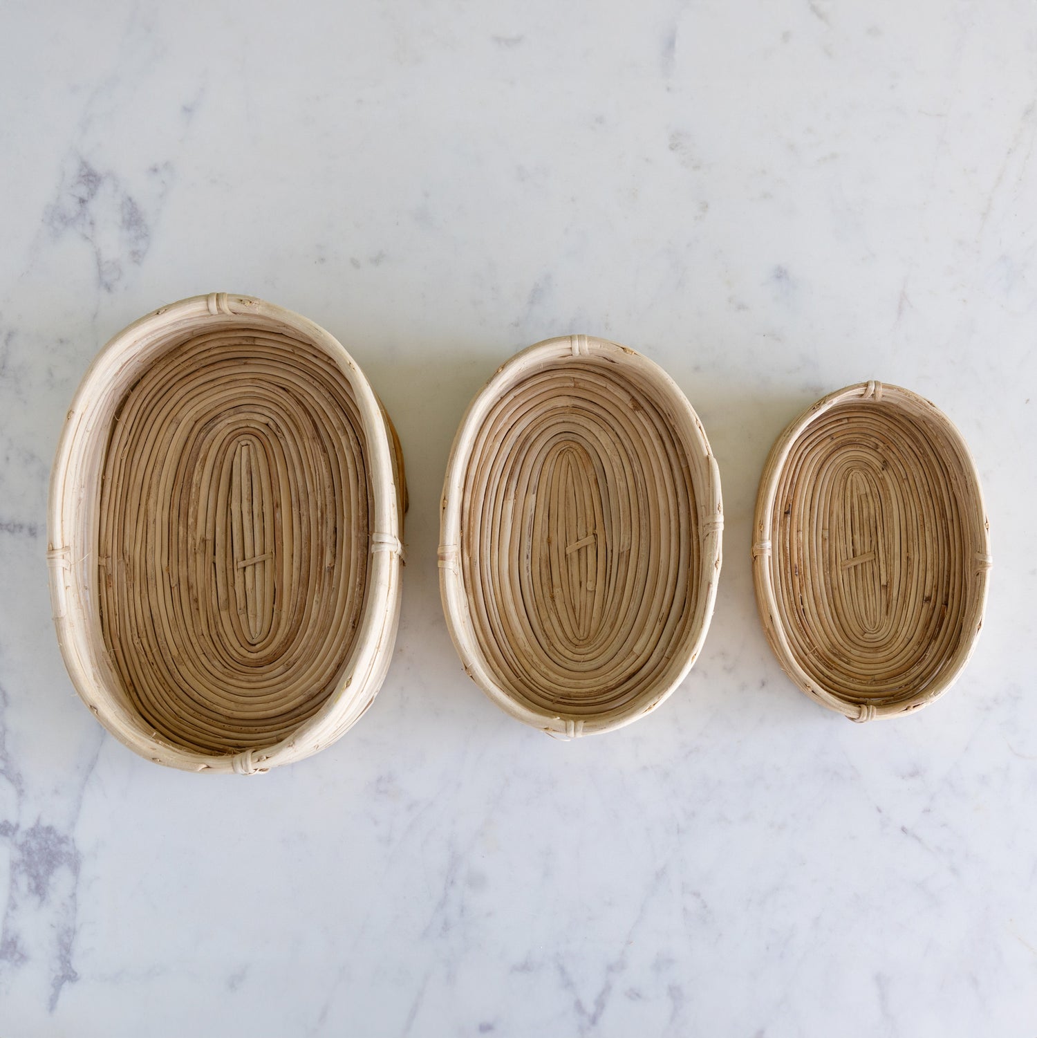 Three woven baskets of different sizes on a marble surface