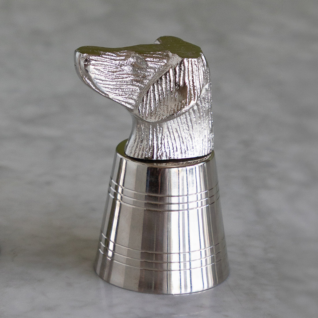 A polished silver metal bottle stopper shaped like a dog&
