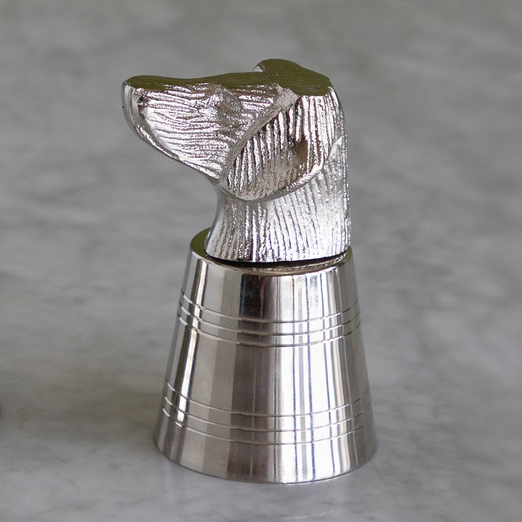 A polished silver metal bottle stopper shaped like a dog&
