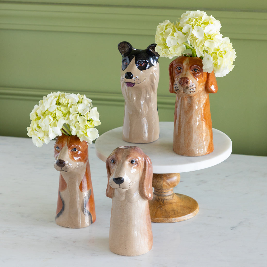 Dog-shaped vases with flowers on a white surface and green wall background