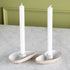 Two oyster shaped candle holders with white taper candles in them. 
