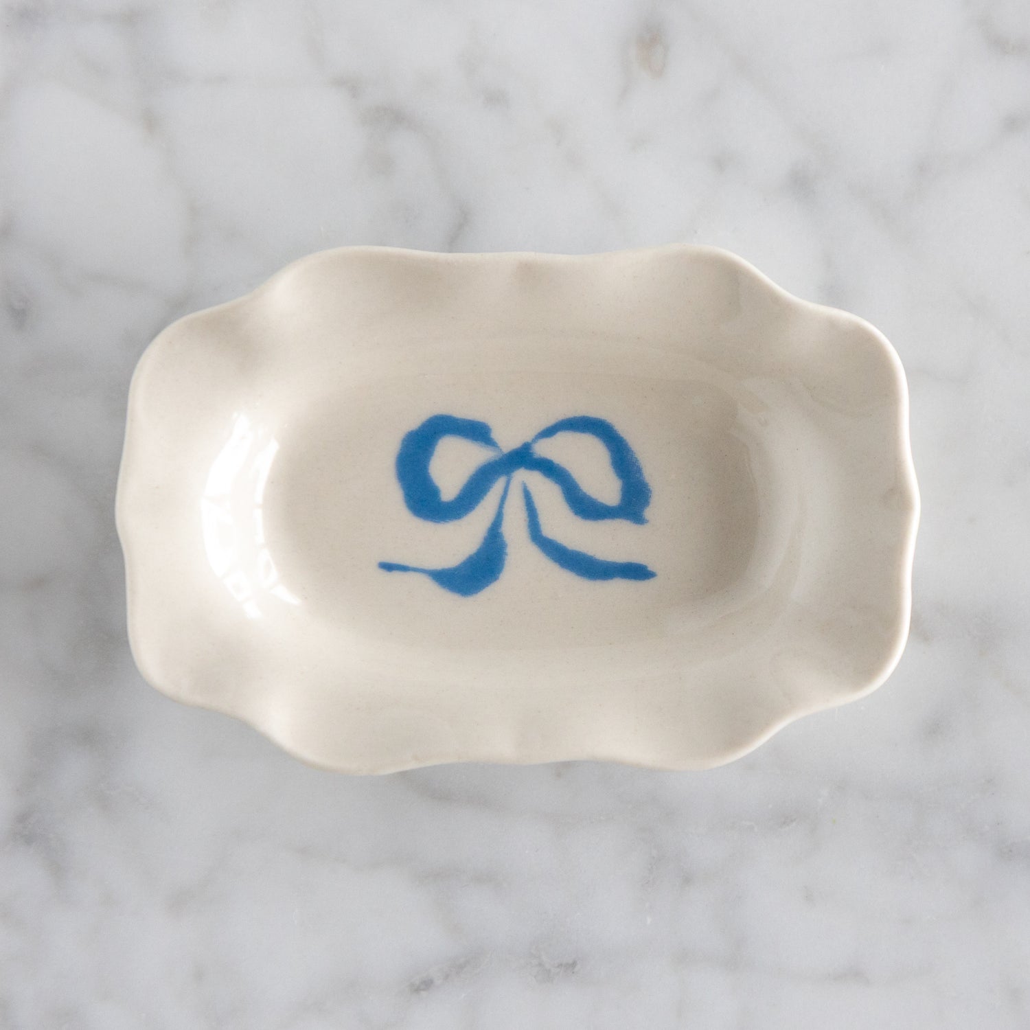 White ceramic dish with blue bow design on a marble surface.