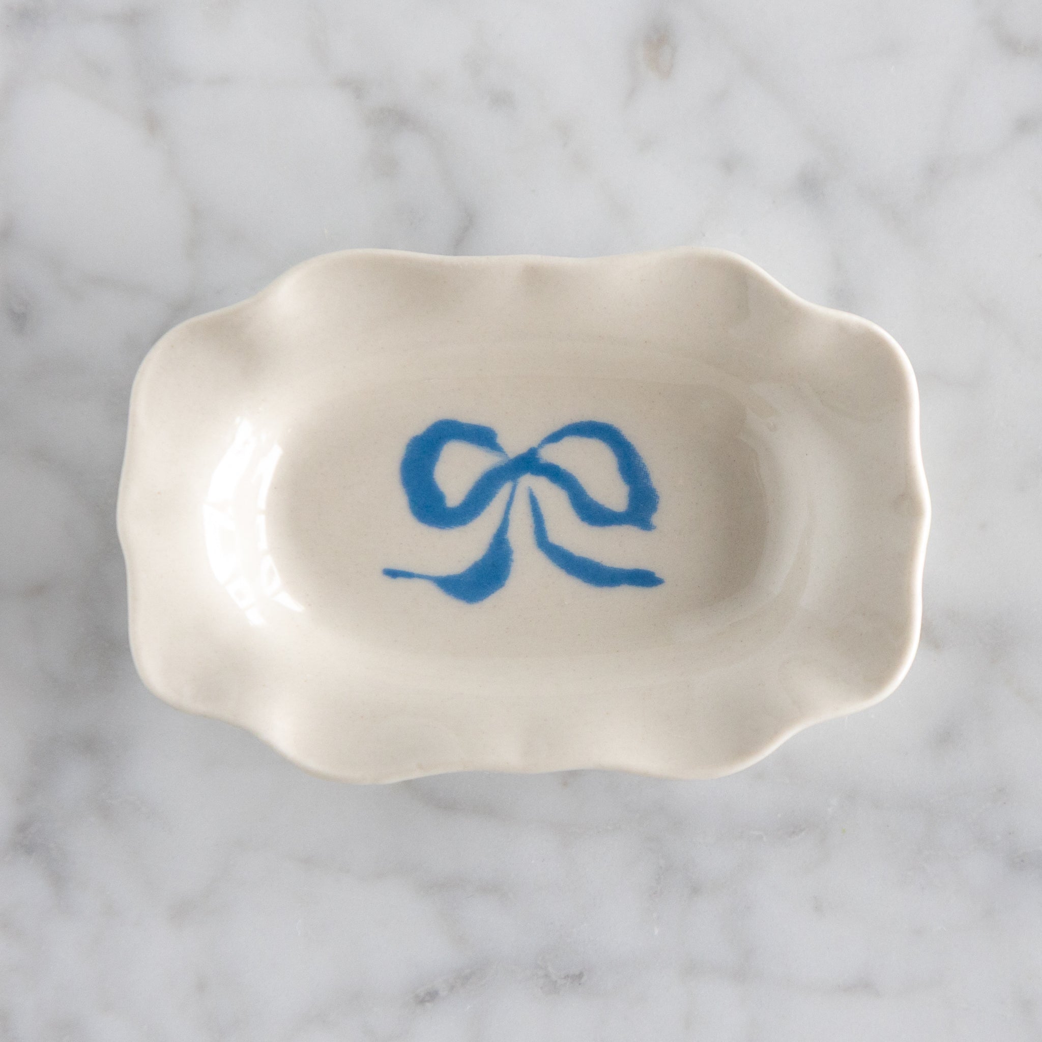 White ceramic dish with blue bow design on a marble surface.
