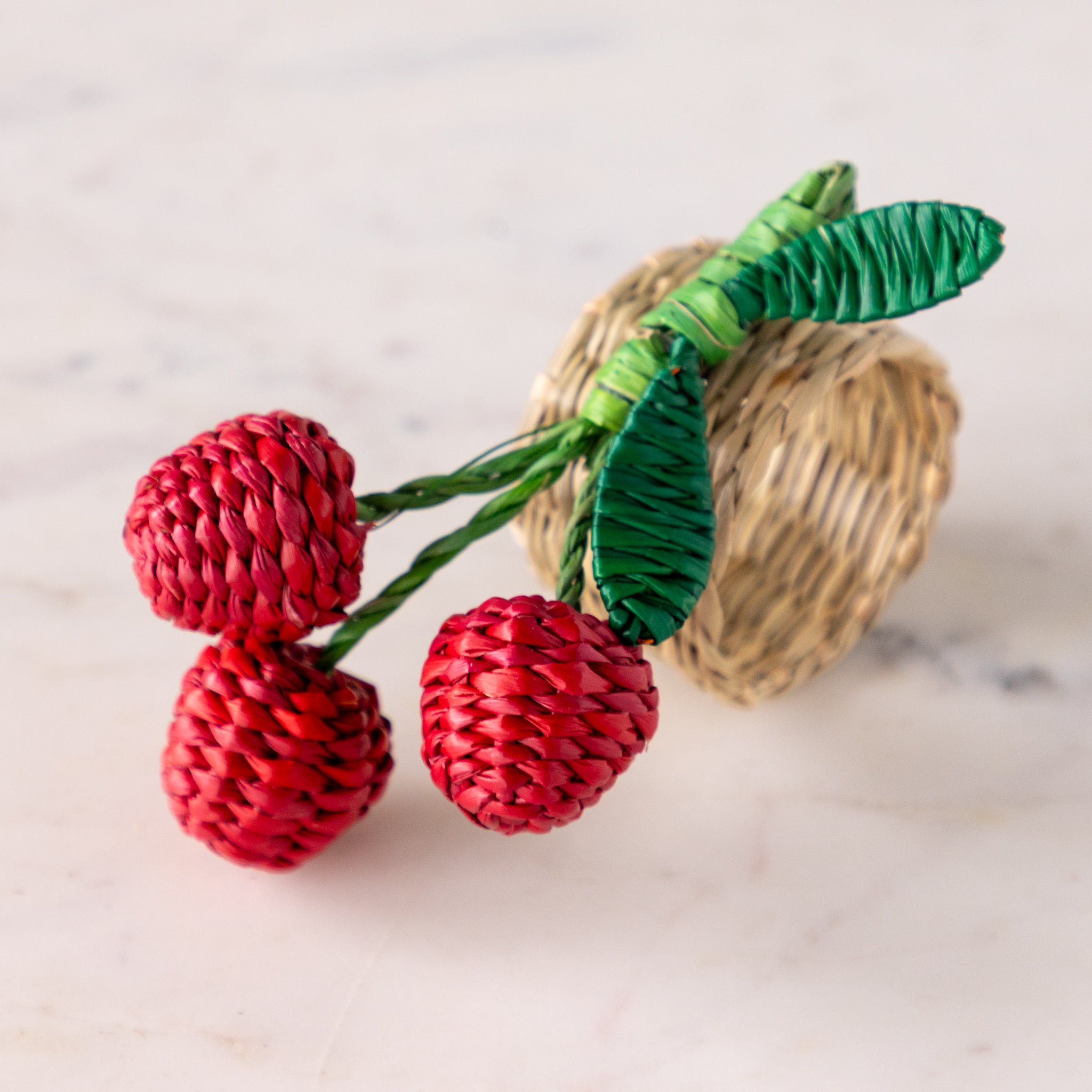 Red berries with green leaves napkin ring on a marble surface.