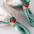 Green napkins with strawberry-themed napkin rings on a white surface.