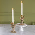 Two Bird Shaped Taper Holders with lit candles on a marble table and green wall background.