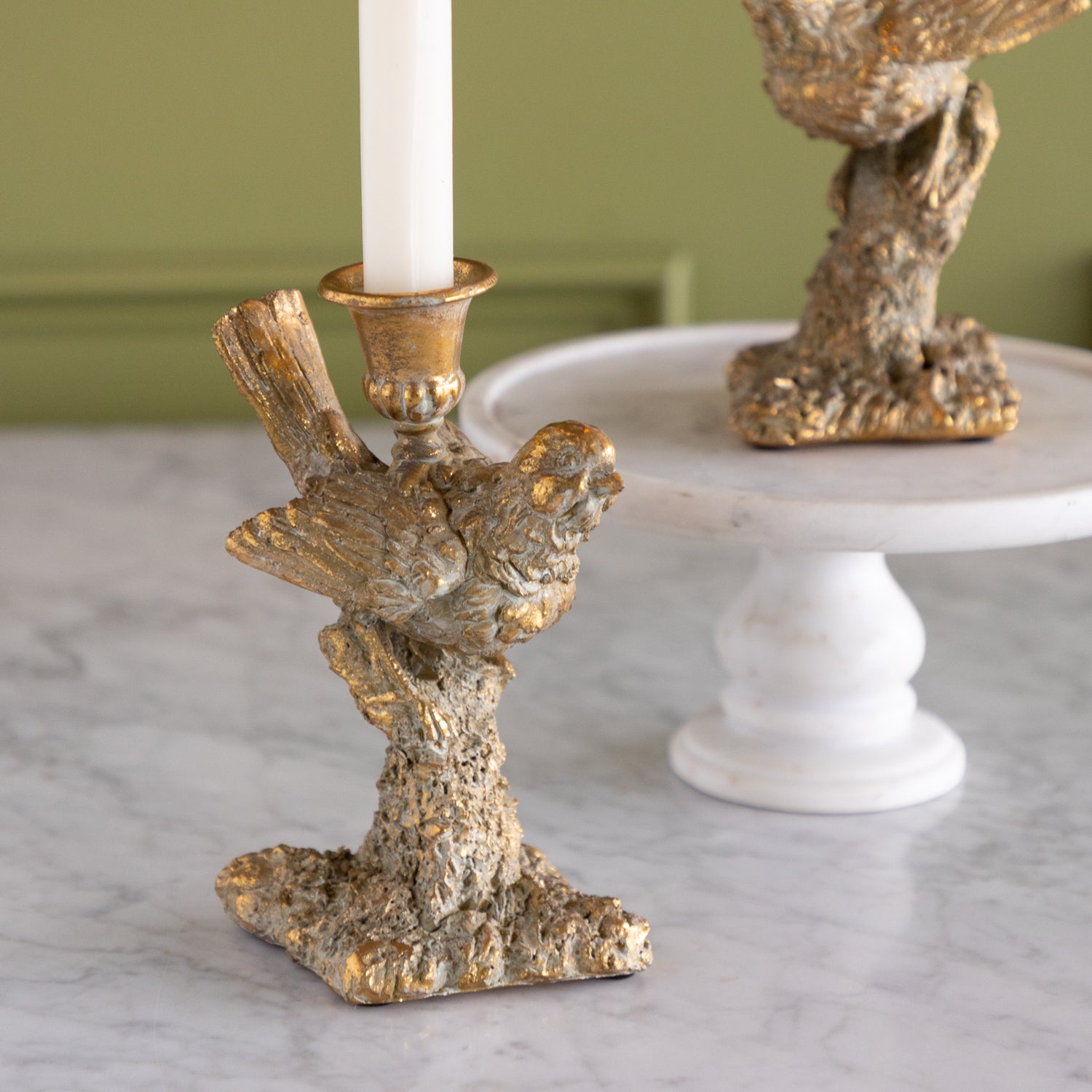 Decorative candle holder with bird design on a neutral background.