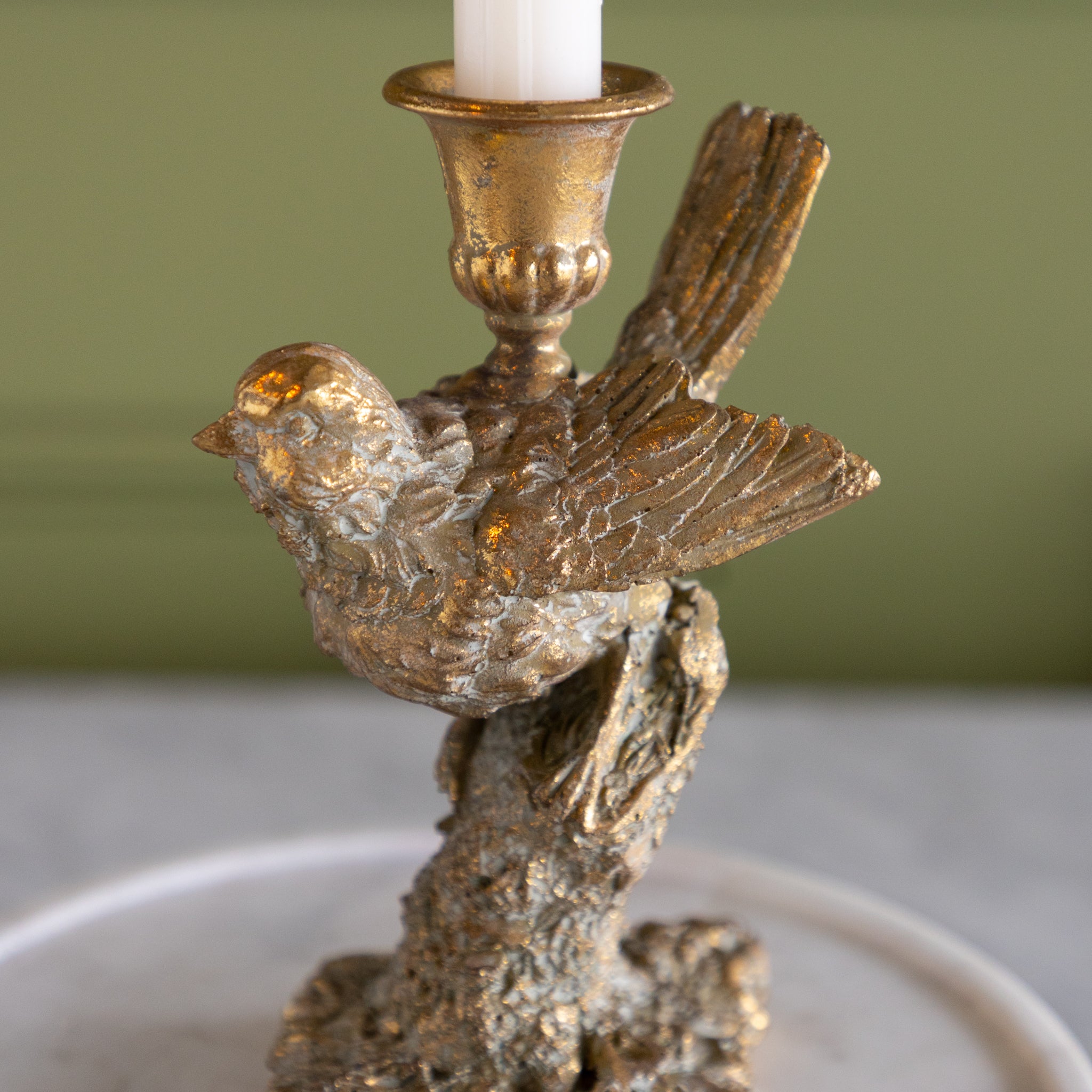 Decorative candle holder with bird design on a neutral background.