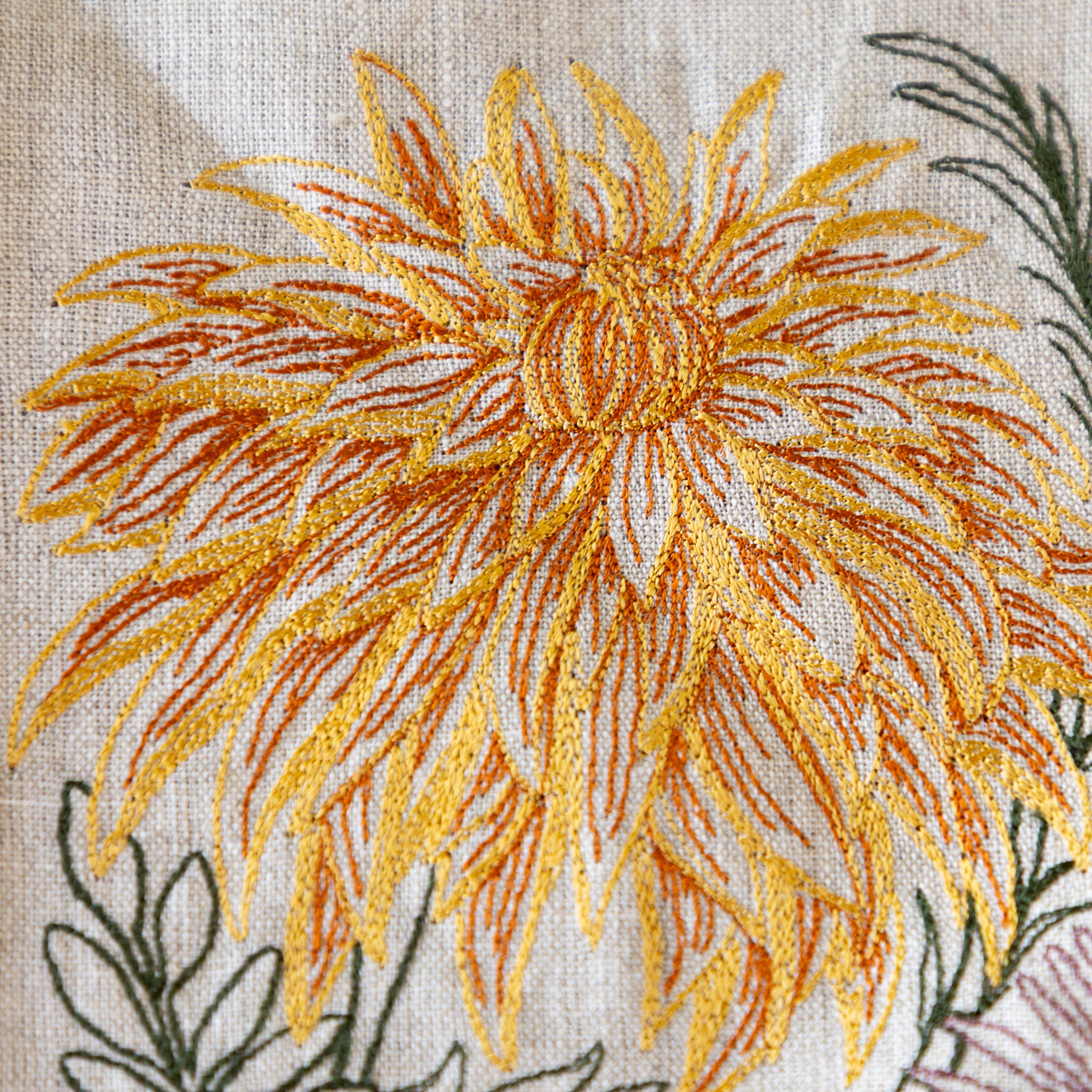 Close-up of embroidered autumn flower design on fabric.