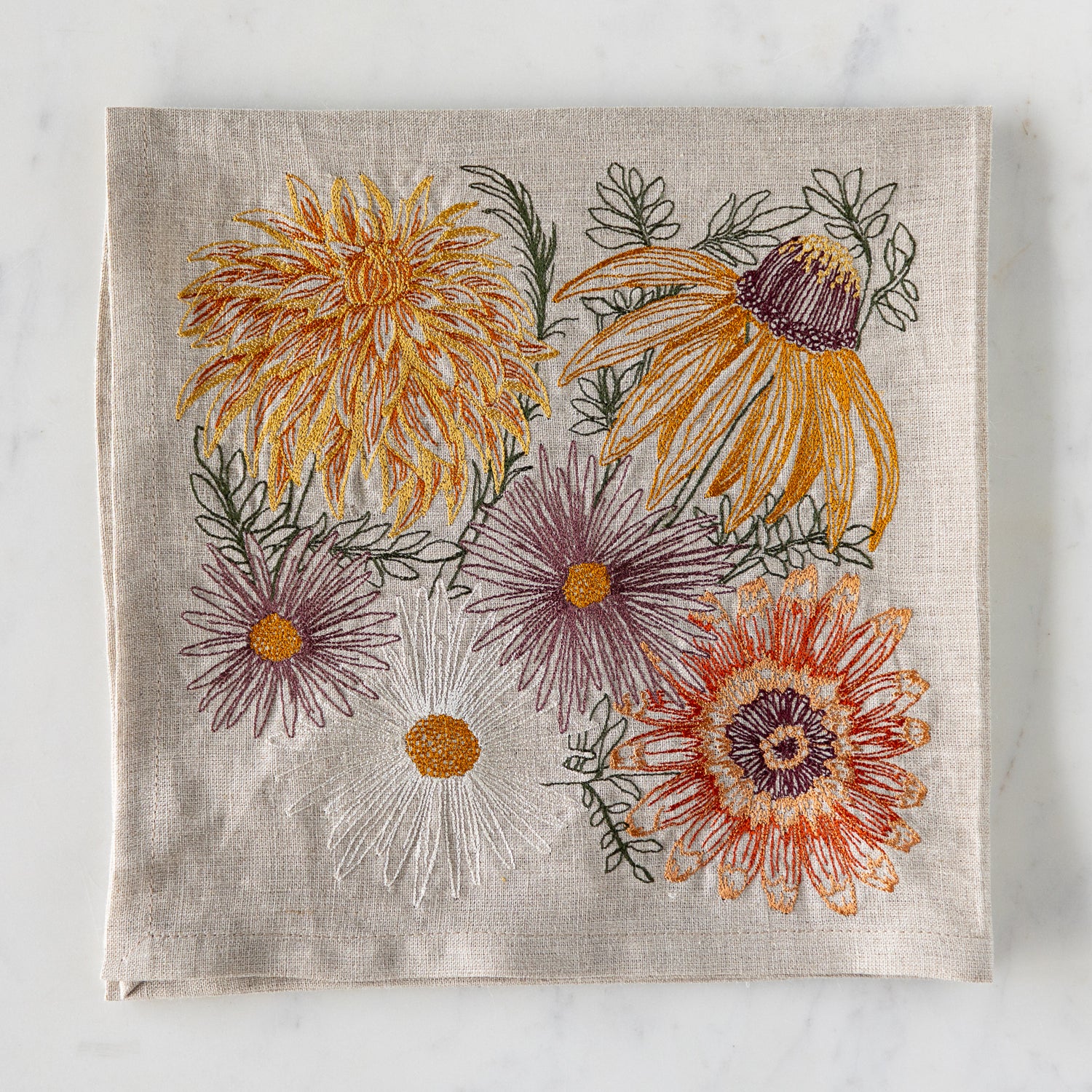 Autumn Blossoms Dinner Napkin folded on a marble table.
