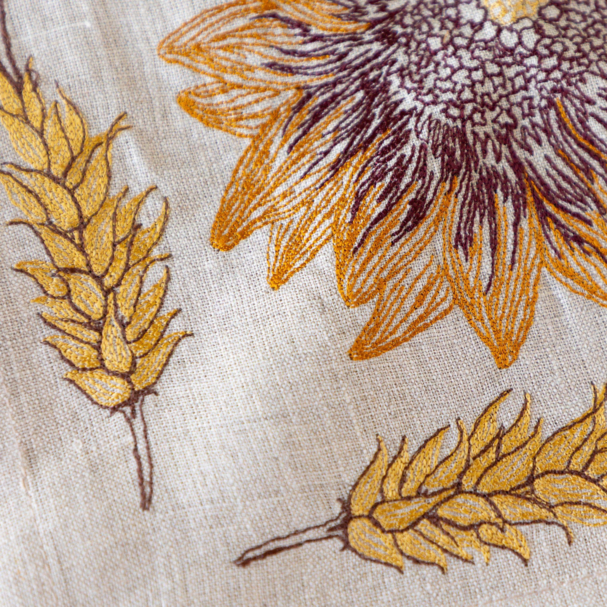 Close-up of embroidered sunflower and wheat patterns on fabric.