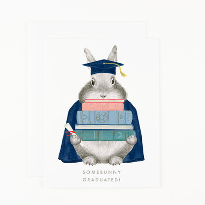 A Somebunny Graduated Card from Dear Hancock, featuring a charming bunny adorned in a cap and gown, clutching books tightly.