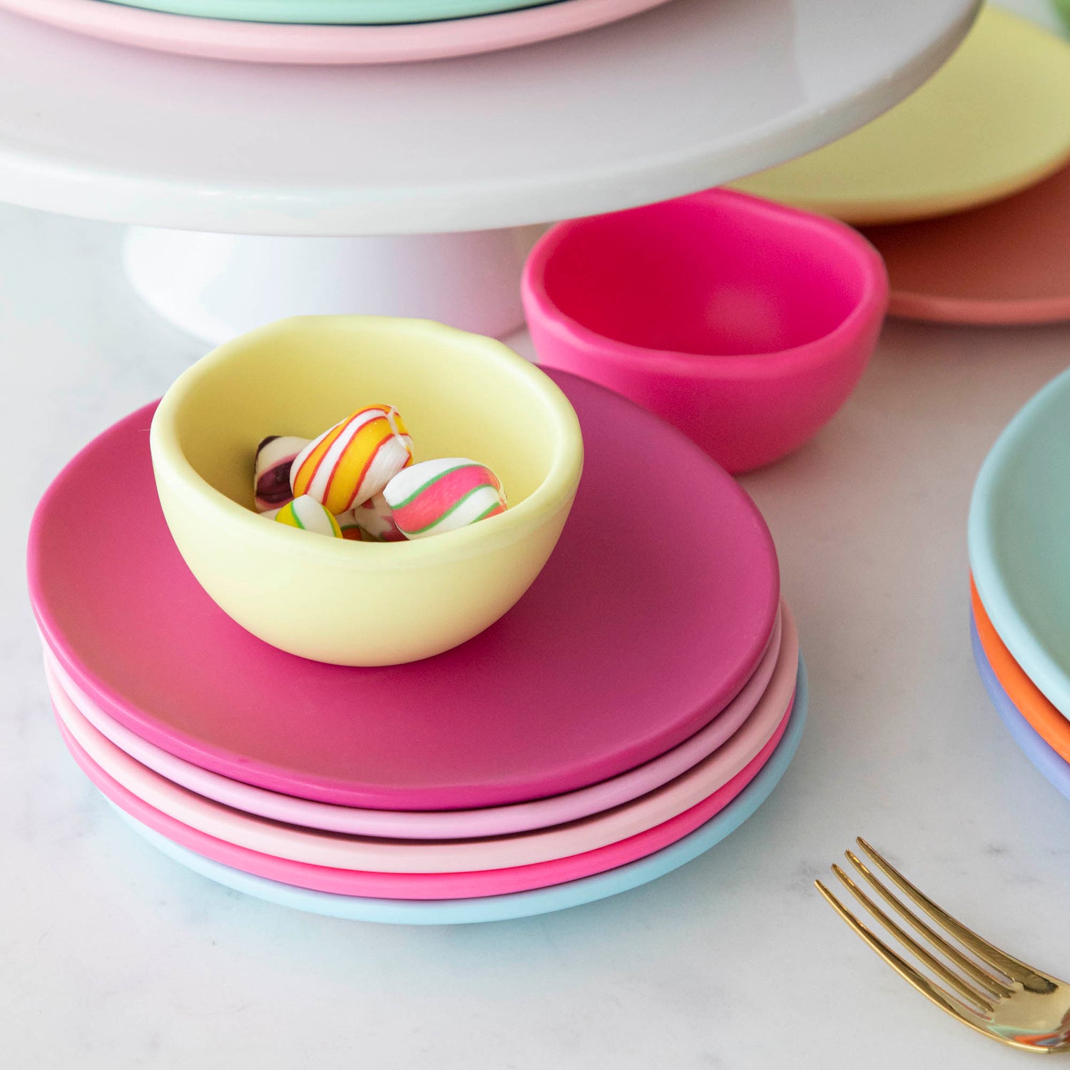 A stack of colorful plates and a bowl on a white table