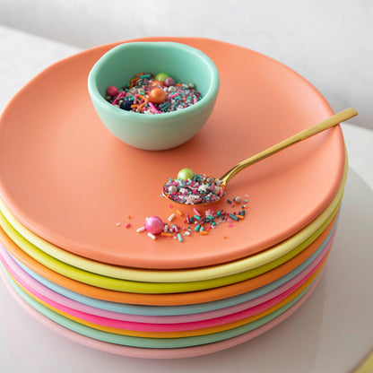 A melamine plate set in a rainbow of colors with delightful sprinkles on them.