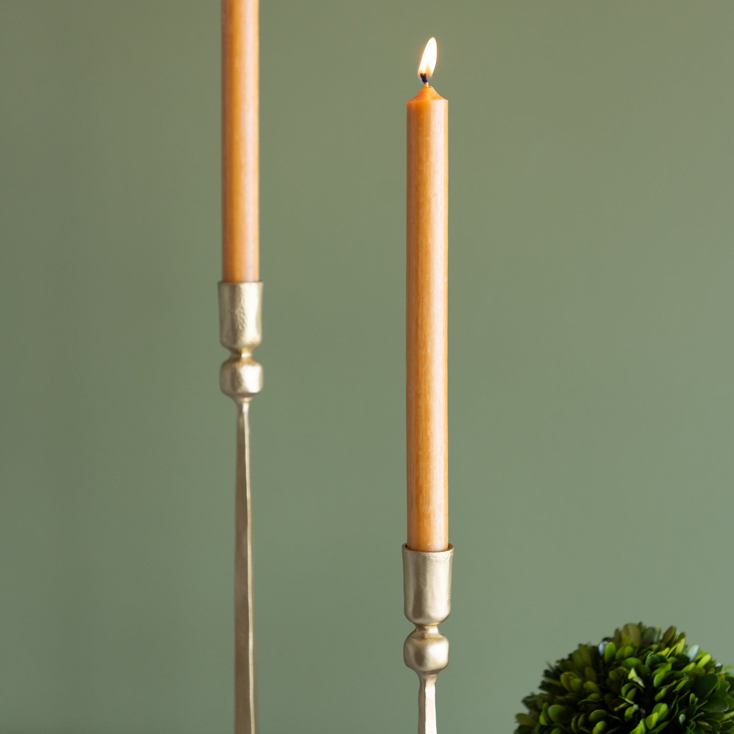 Two candles in decorative holders with a green background