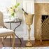 Gold wine cooler with champagne bottle in a stylish room with a fireplace and table.