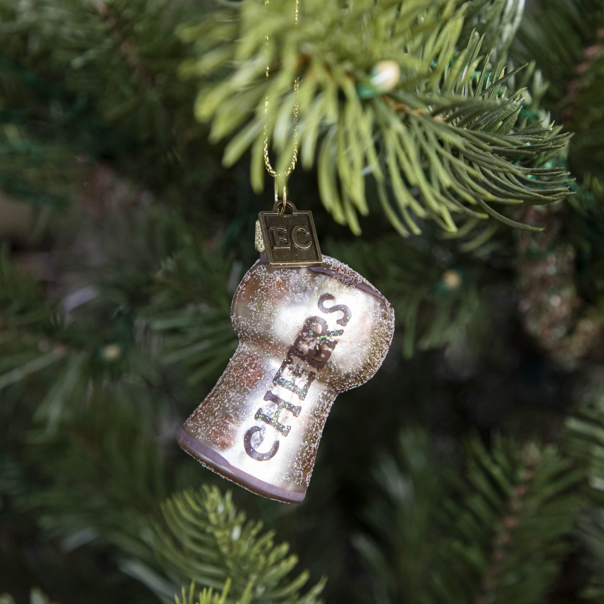 Cheers Cork Ornament hanging on a tree.