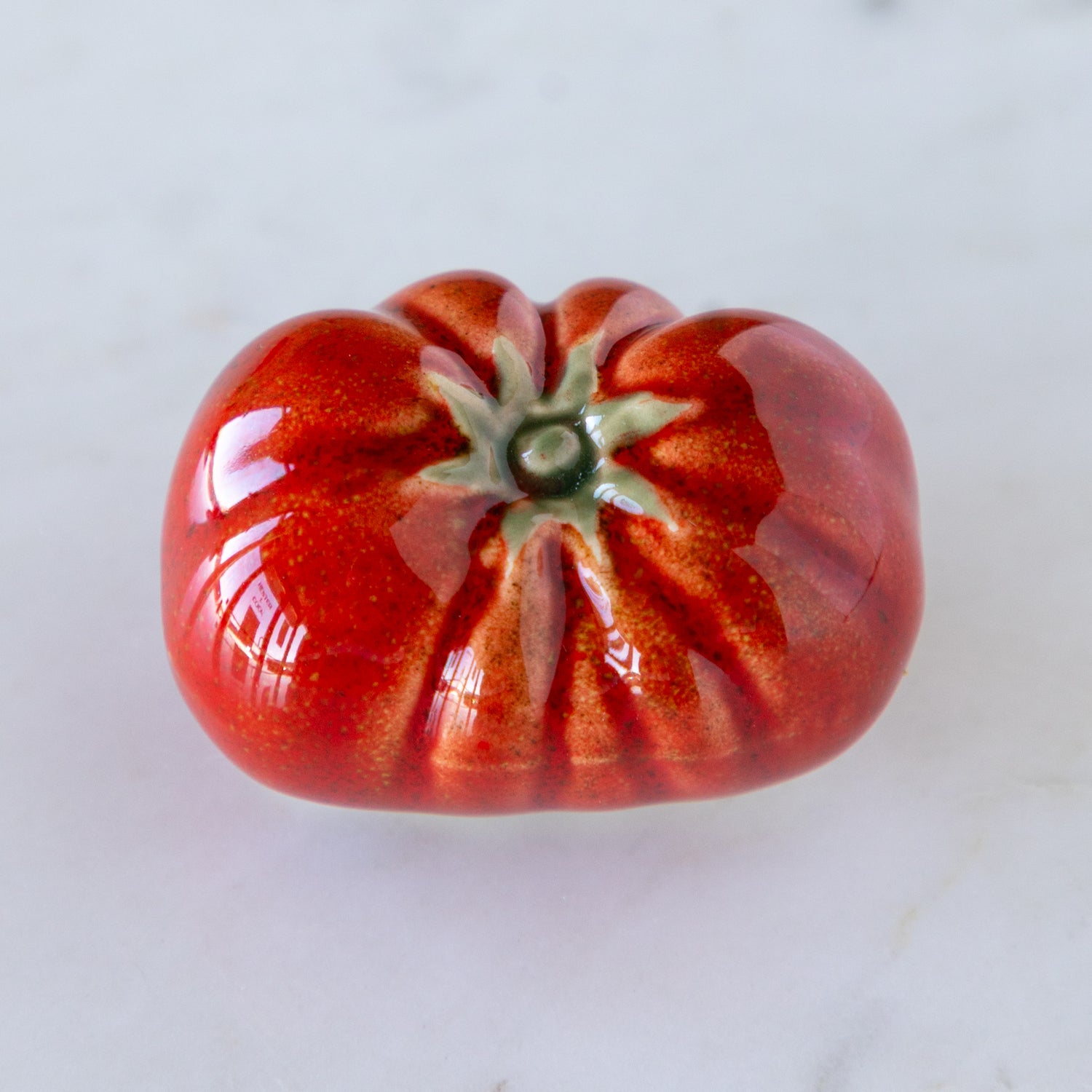 Long, red ceramic tomato on a white background.