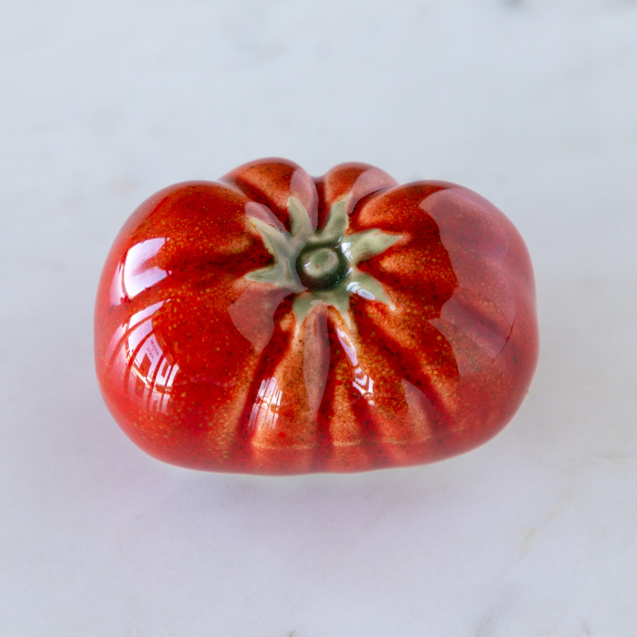 Long, red ceramic tomato on a white background.