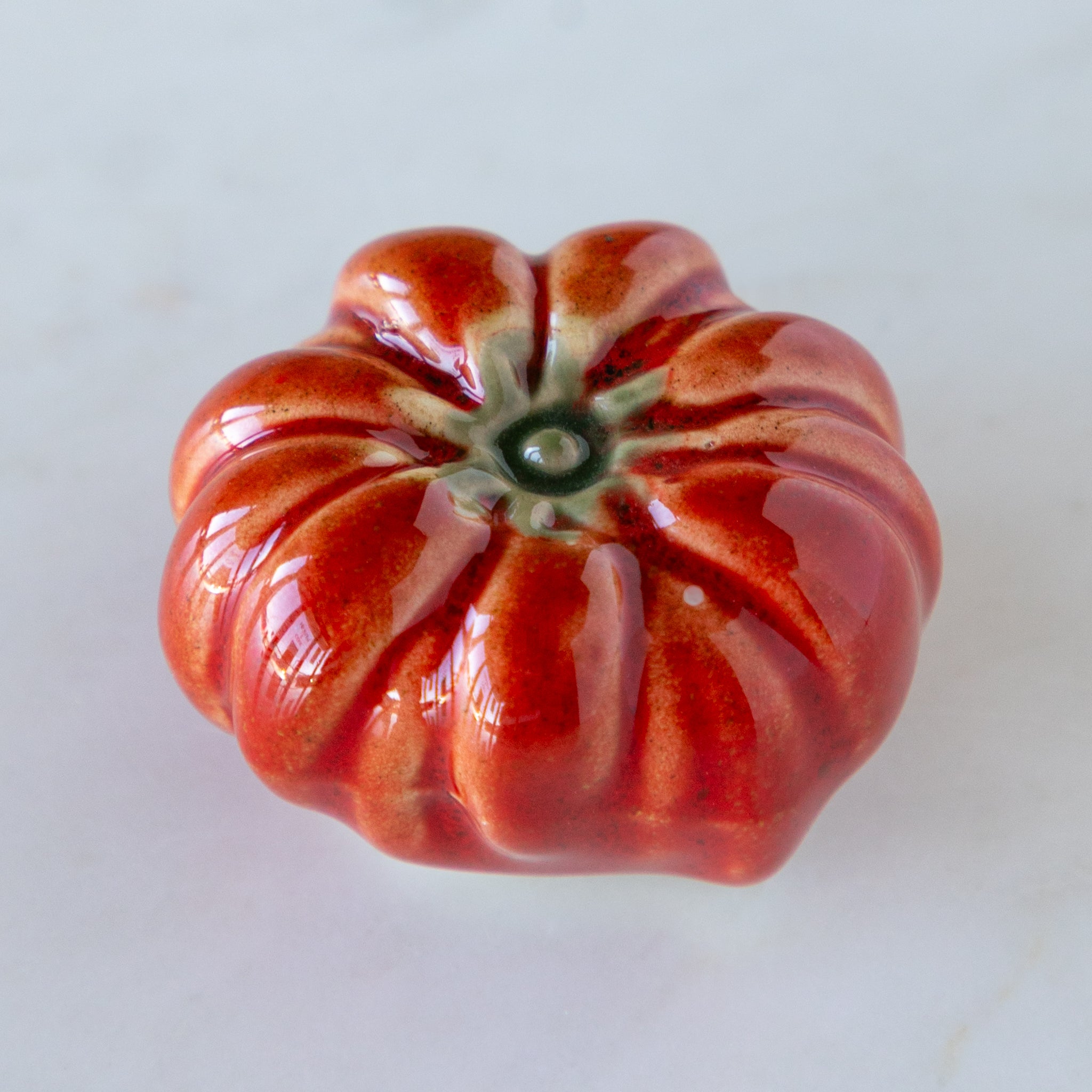 Red ceramic tomato on a white background.