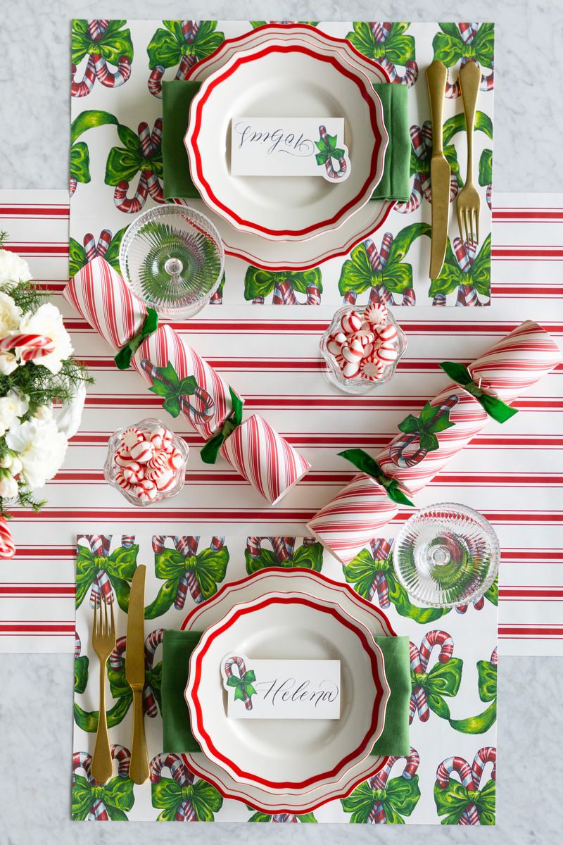 Christmas-themed table setting with red and green patterns on a white tablecloth.
