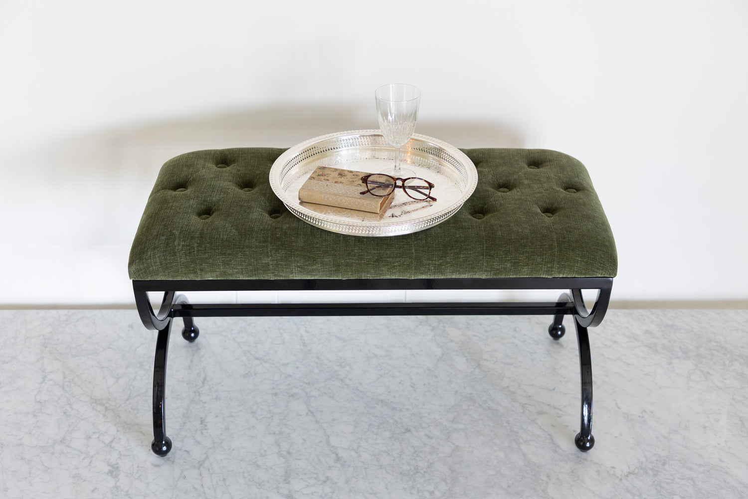 Green upholstered bench with a round metal tray on a white background